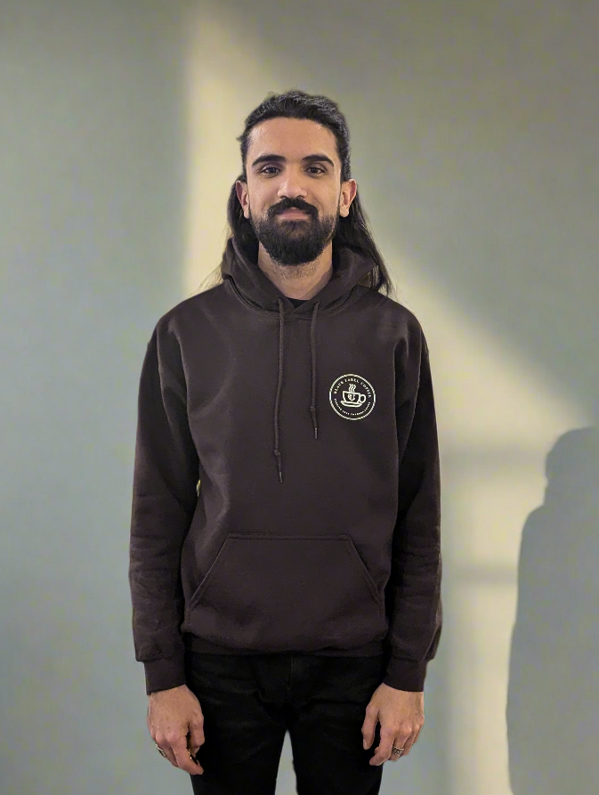 Man wearing a dark hoodie with a logo on a plain background